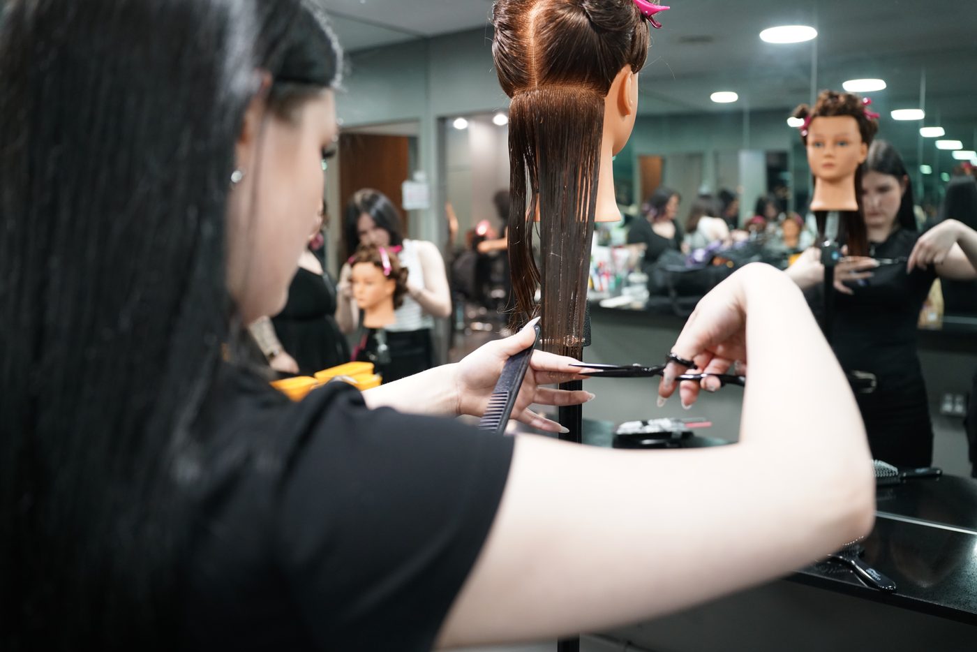 Aveda Institute Vancouver student cutting hair on mannequin first day of hair school